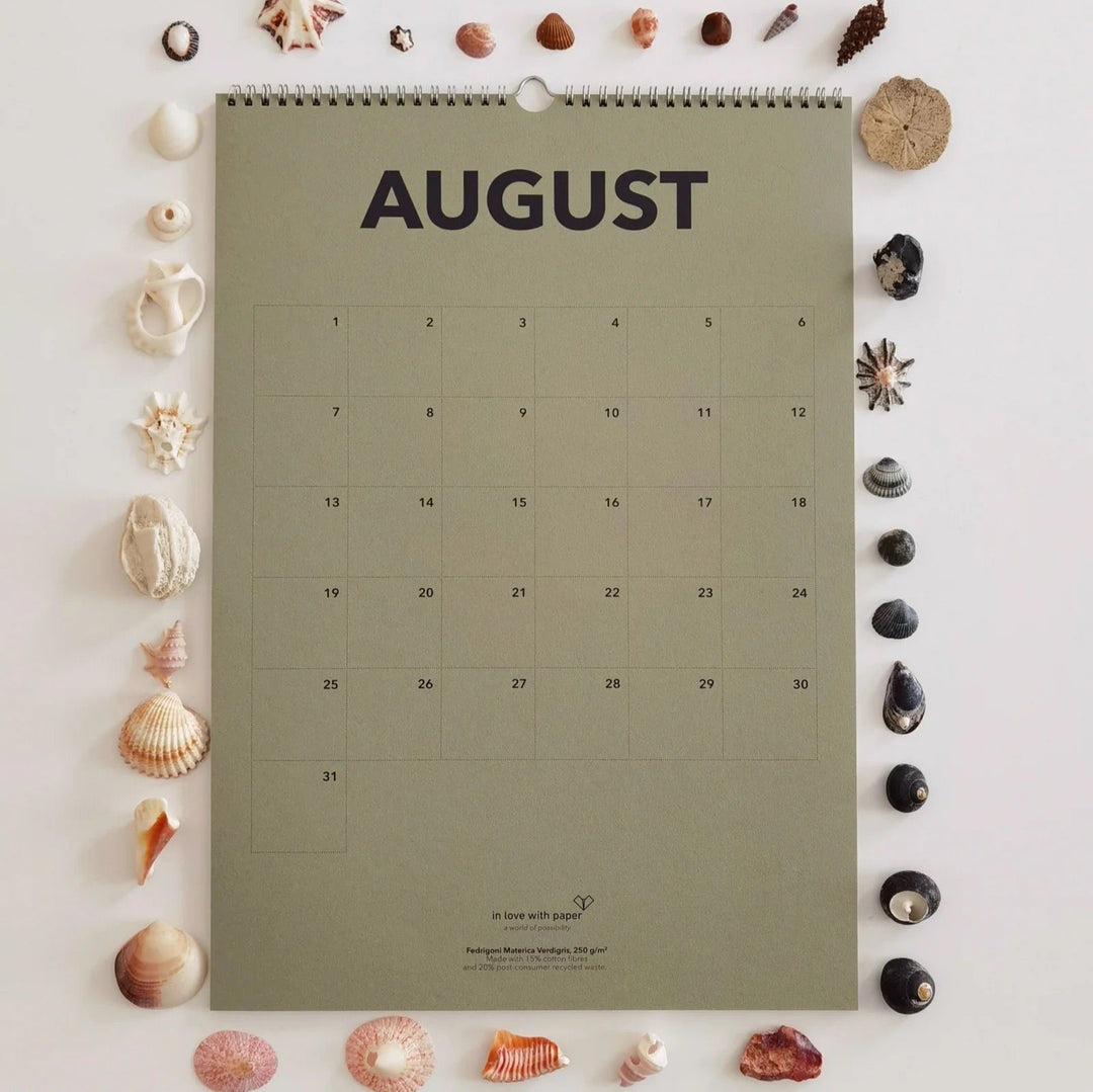The August page from the everlasting calendar, decorated with an assortment of seashells and ocean treasures, creating a coastal summer theme.