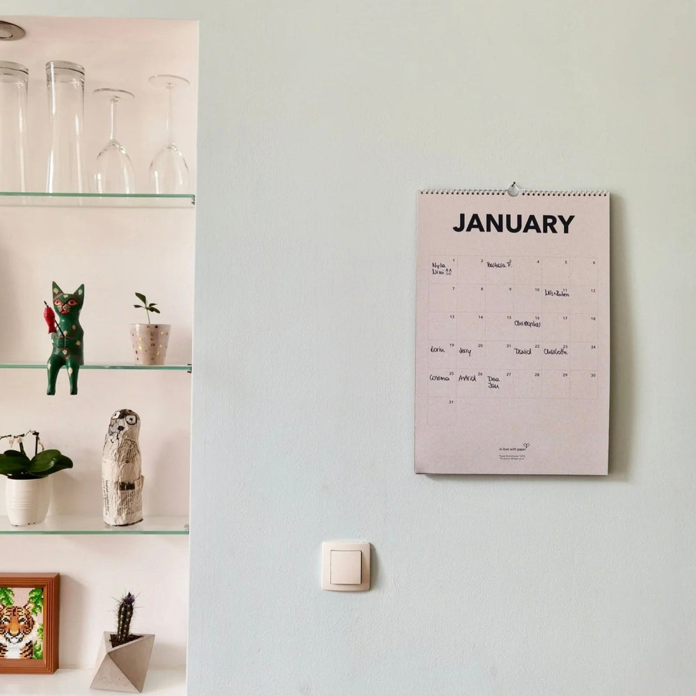 January page of the everlasting calendar hanging on a wall next to a shelf with decorative items.