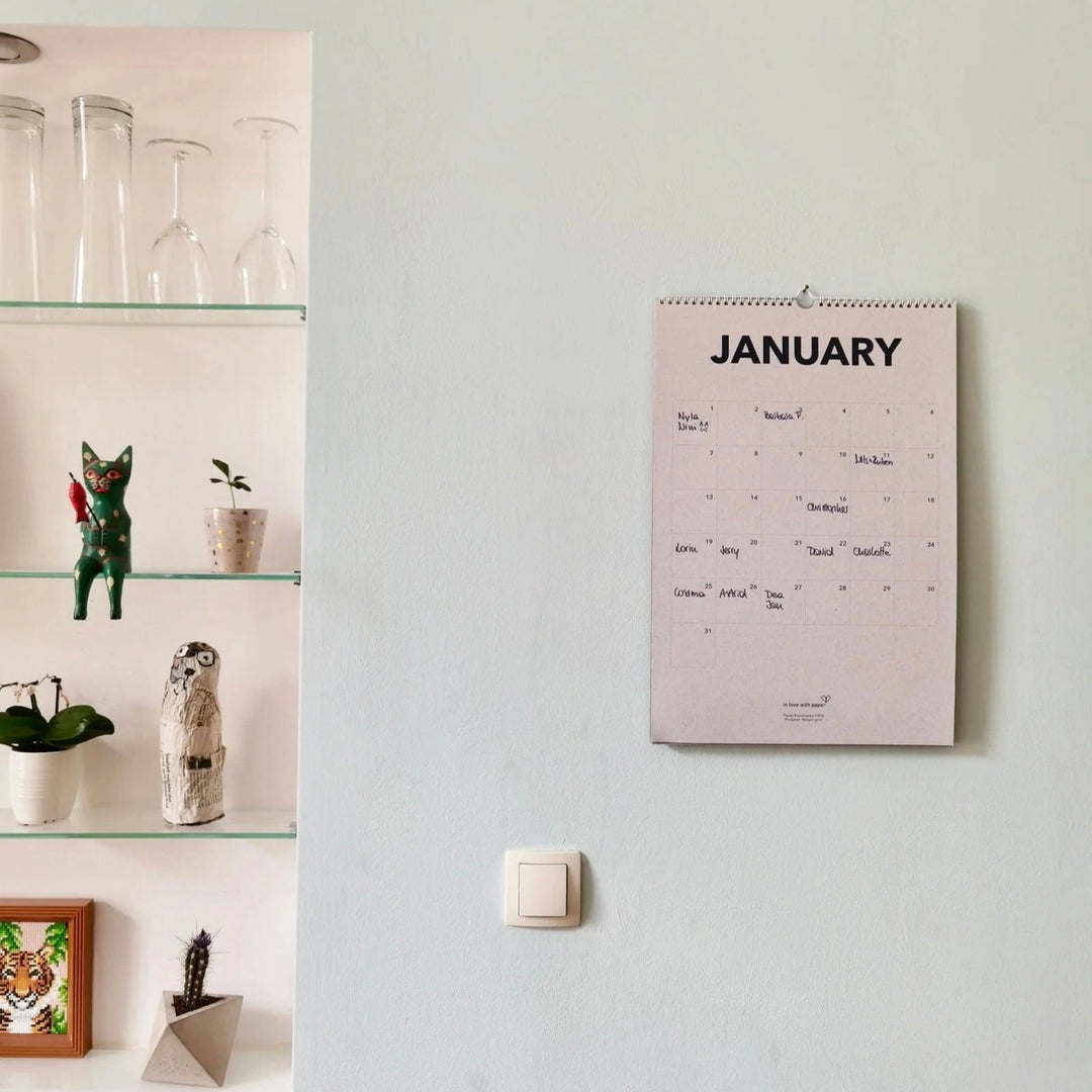January page of the everlasting calendar hanging on a wall next to a shelf with decorative items.