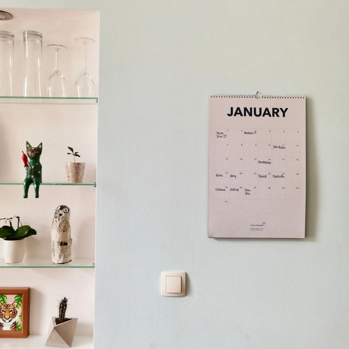 January page of the everlasting calendar hanging on a wall next to a shelf with decorative items.