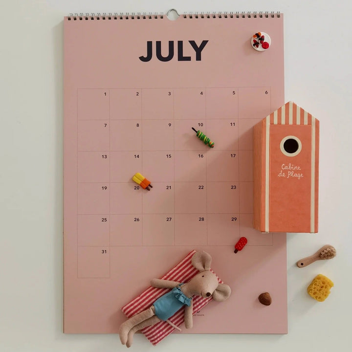July page of the everlasting calendar with playful beach decor, including a striped beach hut and a lounging toy mouse