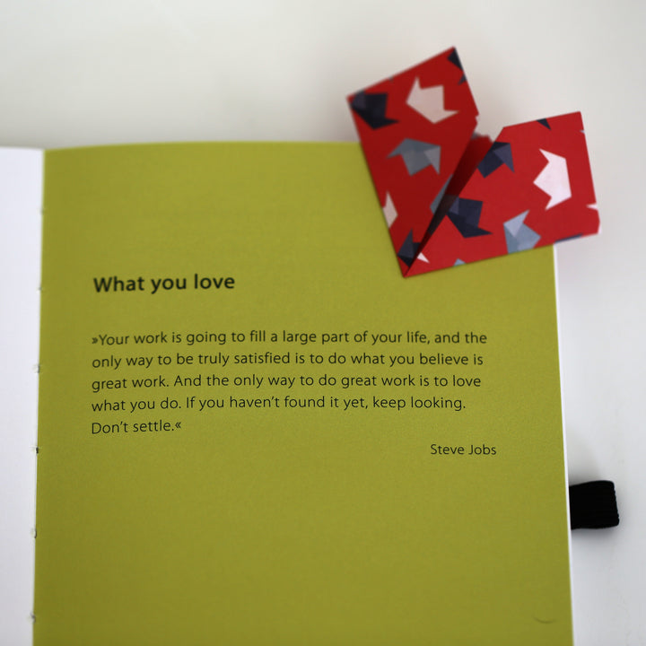 Page from Chapter 1 of the 'Ikigai or A Good Life' book featuring an inspirational quote by Steve Jobs about loving your work, with a red origami bookmark.