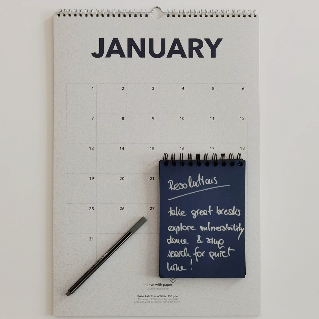 January page of the everlasting calendar with a pen and notebook listing New Year's resolutions.
